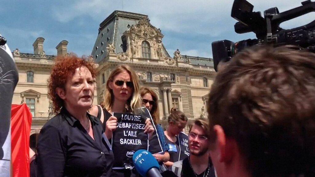 Nan Golding steht in einer Gruppe von Aktivistinnen vor dem Louvre in Paris und gibt ein Fernsehinterview.